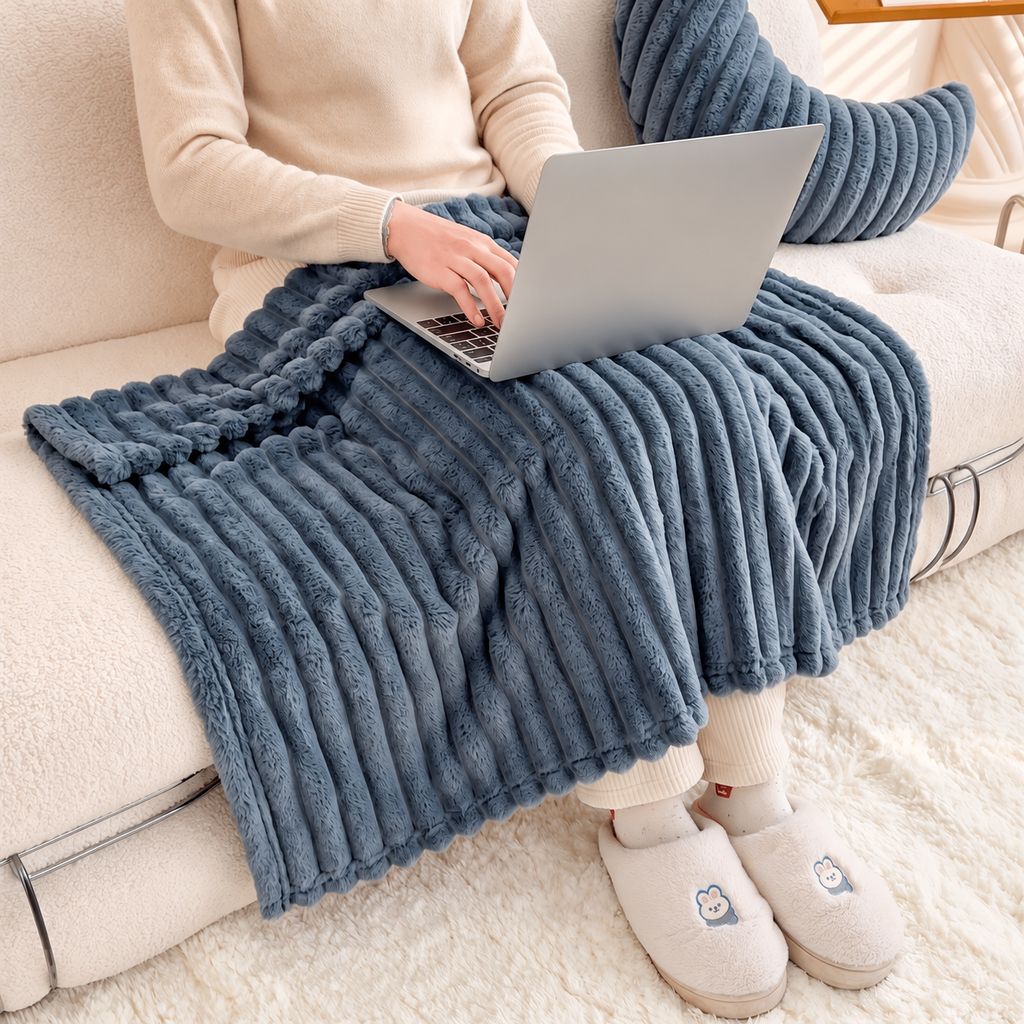 Dark gray faux fur throw blanket covering a seated laptop user on a sofa