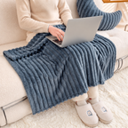 Dark gray faux fur throw blanket covering a seated laptop user on a sofa