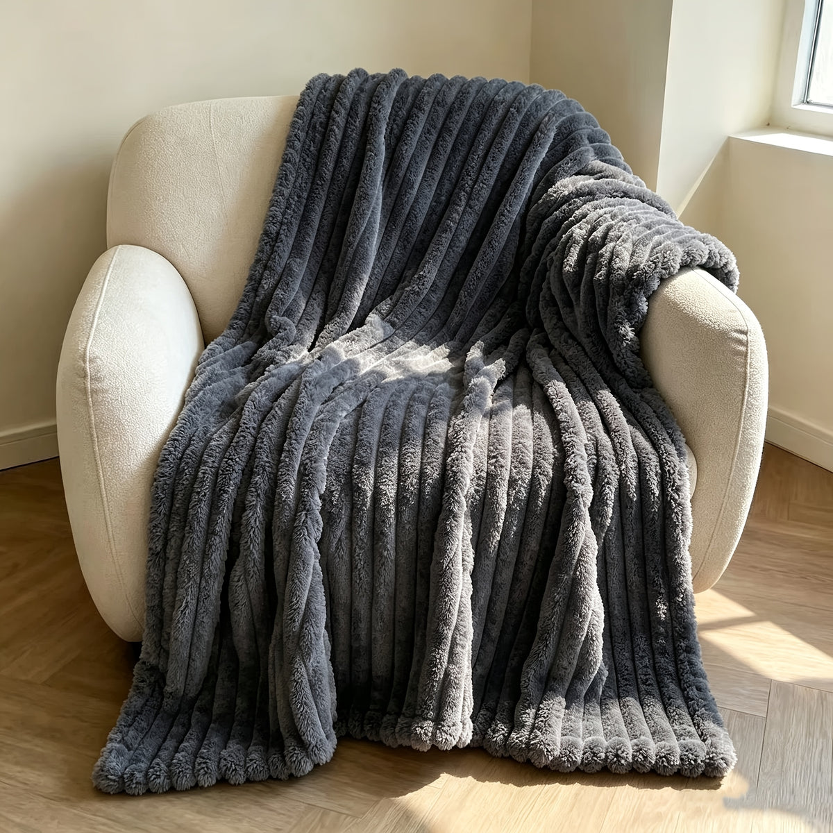 Dark gray faux fur throw blanket covering a cream armchair.