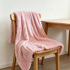 Pink faux fur throw blanket draped over a wooden chair.