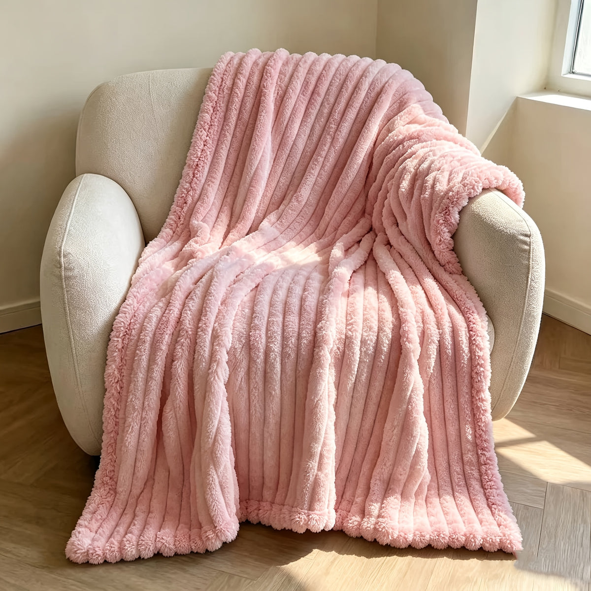 Pink faux fur throw blanket covering a cream armchair.