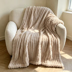 Beige faux fur throw blanket draped over a cream armchair.