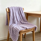 Purple faux fur throw blanket draped over a wooden chair.