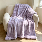 Purple faux fur throw blanket covering a cream armchair.