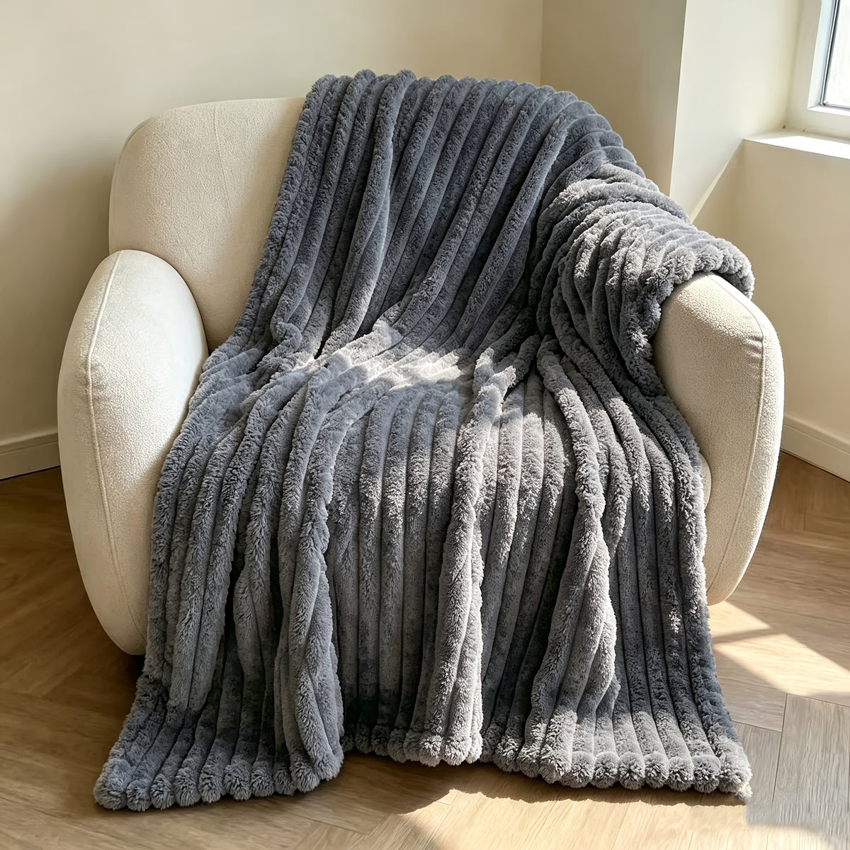 Light gray faux fur throw blanket draped over a cream armchair.