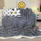 Light gray faux fur throw blanket covering a bed.