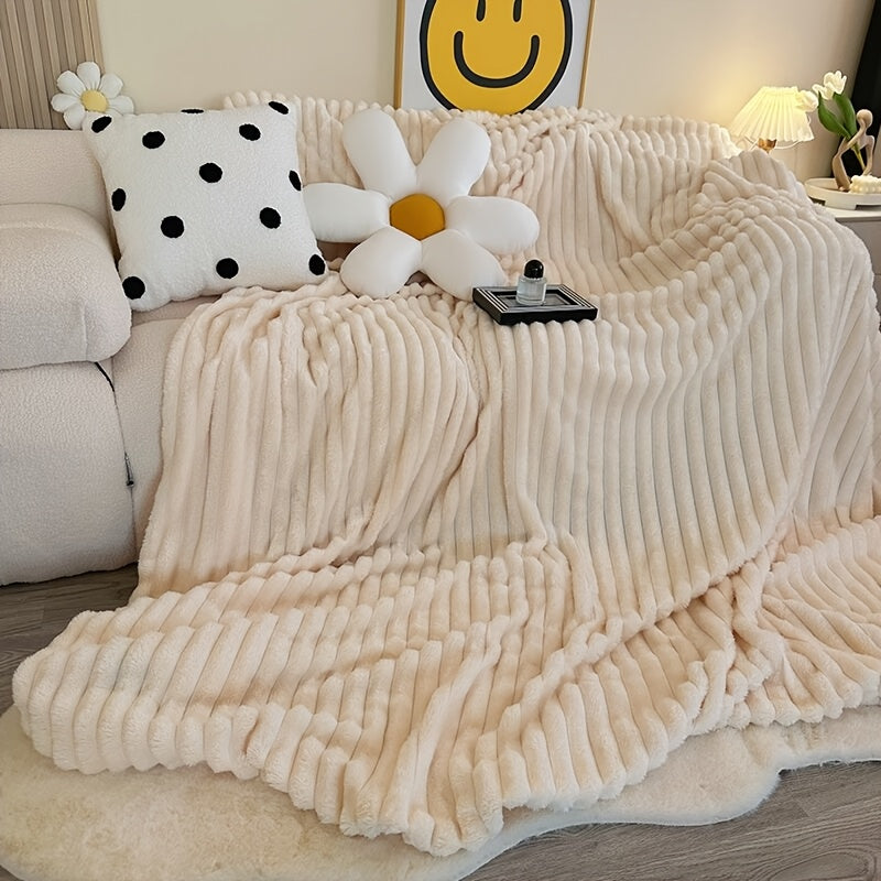 Beige faux fur throw blanket spread across a bed.