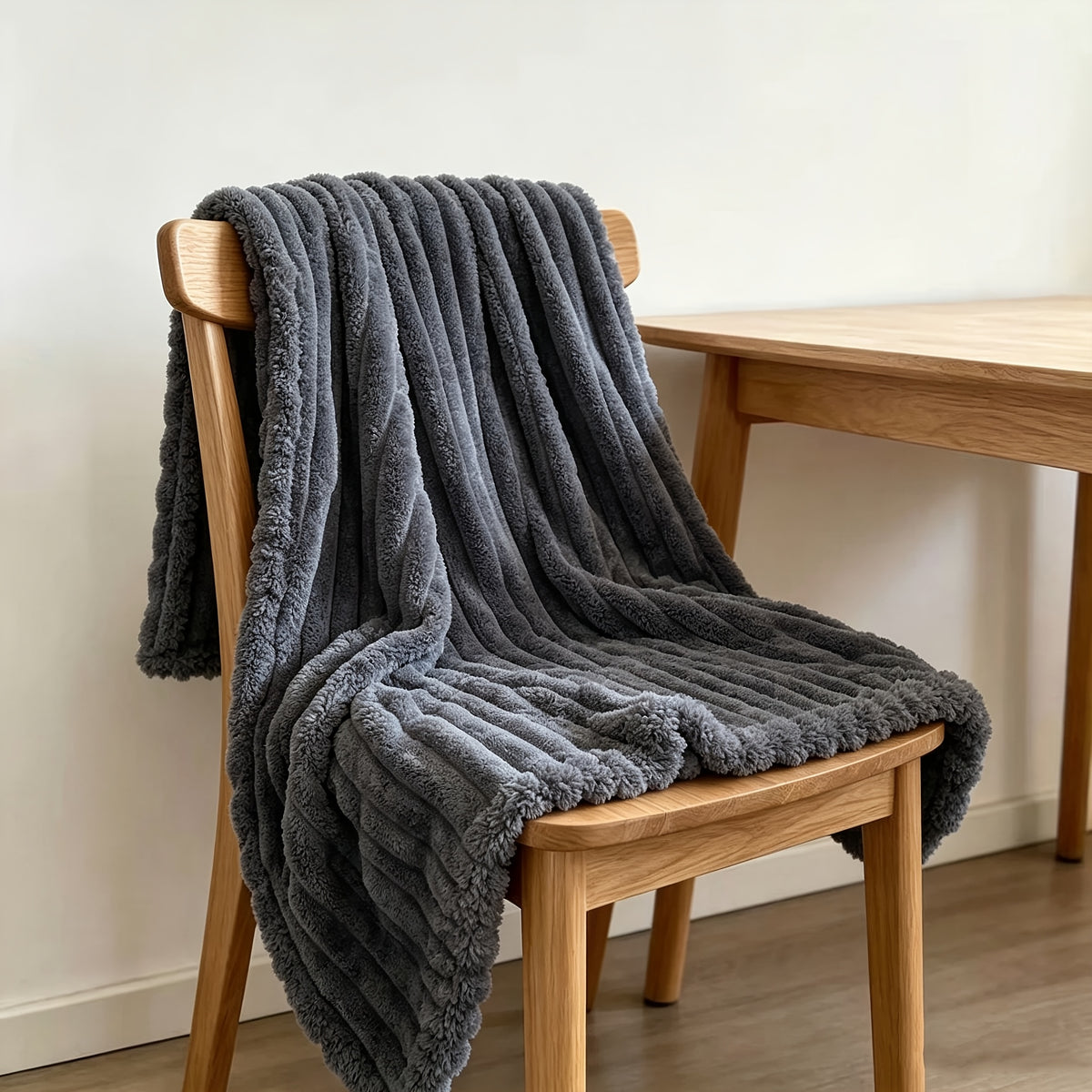 Dark gray faux fur throw blanket draped over a wooden chair.