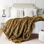 Brown faux fur throw blanket across the foot of a white bed.