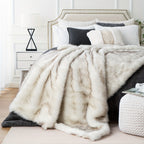 White tipped faux fur blanket across a bed in a bright bedroom.