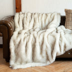 White tipped faux fur blanket draped across a tufted leather couch.