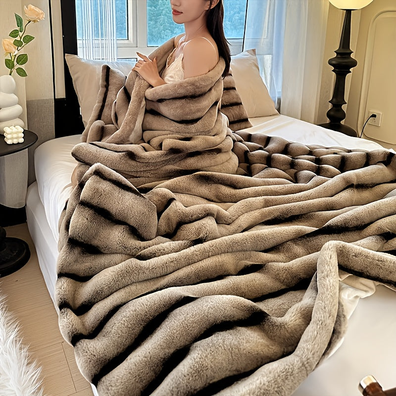 A woman wrapped in a beige striped faux fur throw blanket.