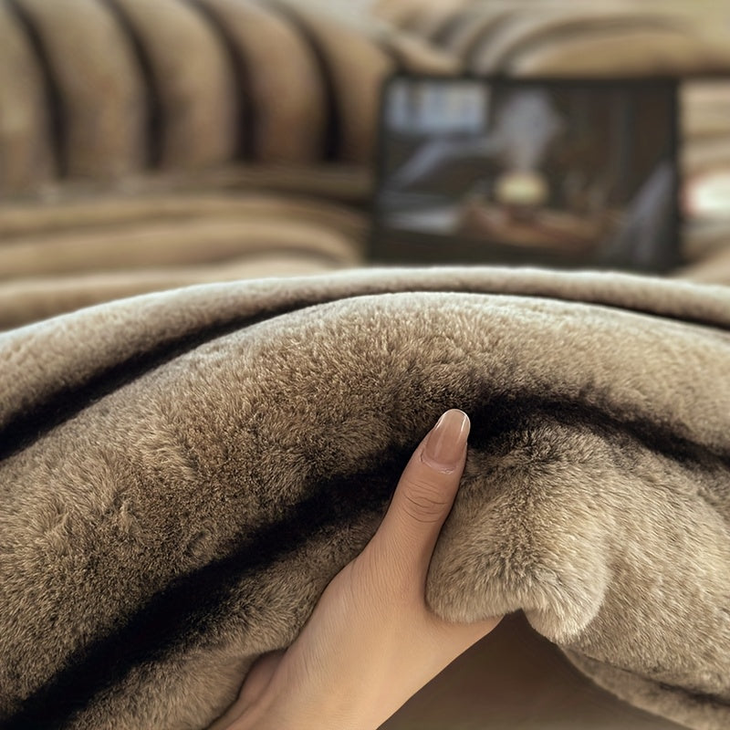 A hand holding the beige pile of a faux fur throw blanket.