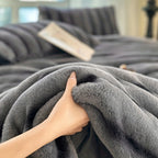 Hand holding the edge of a gray plush blanket.