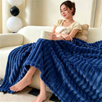 Woman seated on a cream couch with a royal blue raised striped blanket.