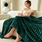Woman seated on a couch with a dark green raised striped blanket.
