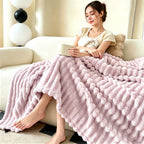 Woman seated on a couch with a pale purple raised striped blanket.