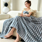 Woman seated on a couch with a blue gray raised striped blanket.