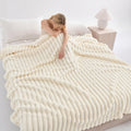 Woman resting on a bed under a white ribbed faux fur blanket.