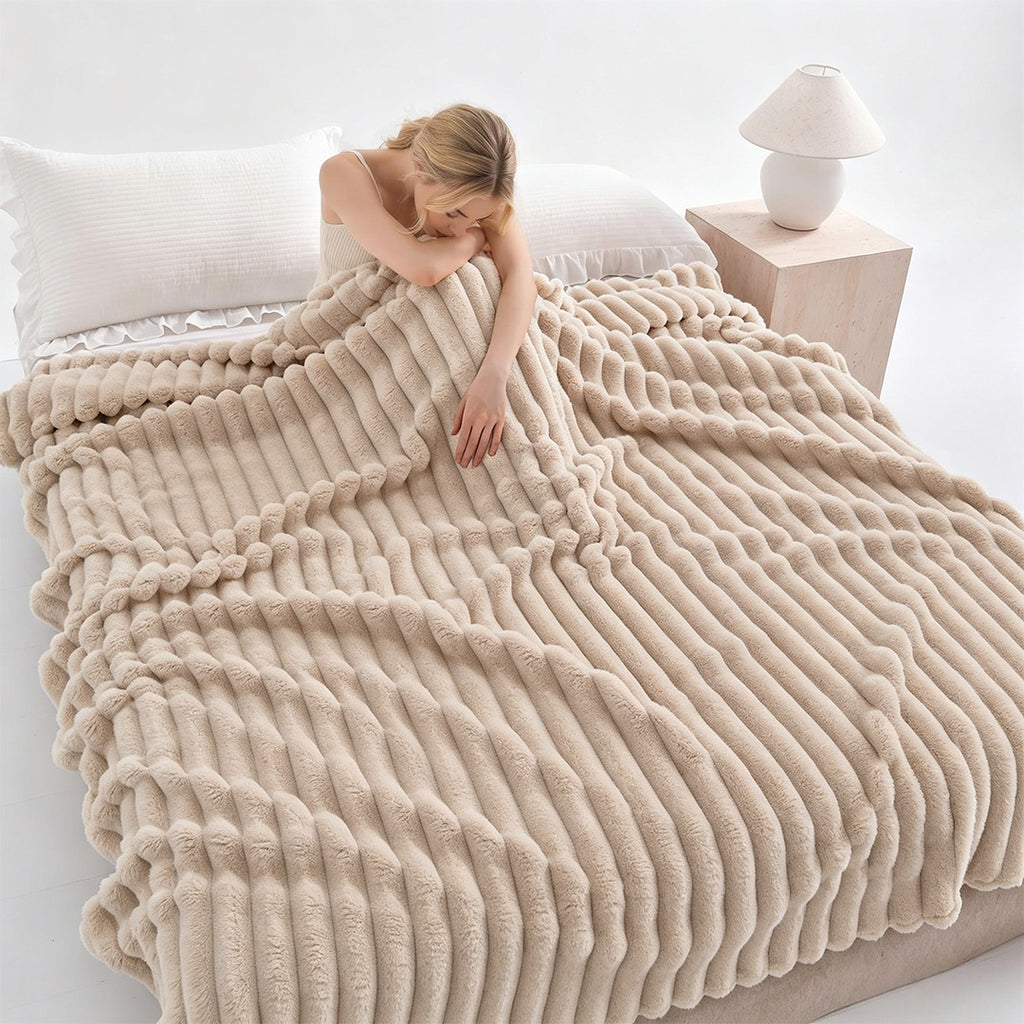 Woman resting on a bed under a khaki ribbed faux fur blanket.