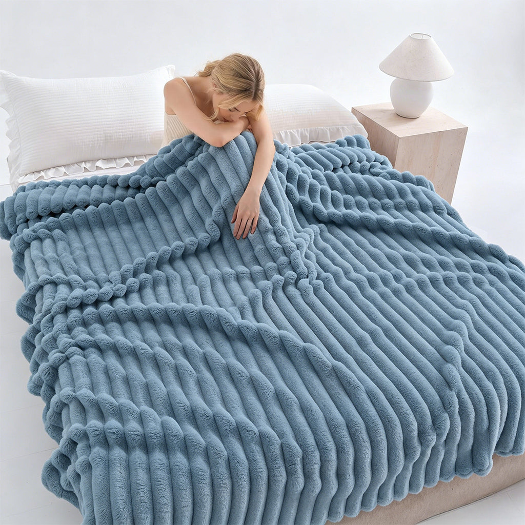 Woman resting on a bed under a blue ribbed faux fur blanket.