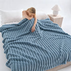 Woman resting on a bed under a blue ribbed faux fur blanket.