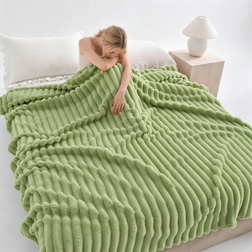 Woman resting on a bed under a green ribbed faux fur blanket.