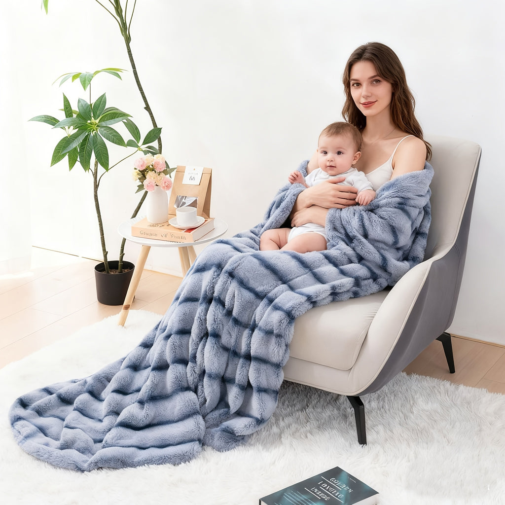 Woman holding a child while covered with a blue ribbed faux fur blanket.