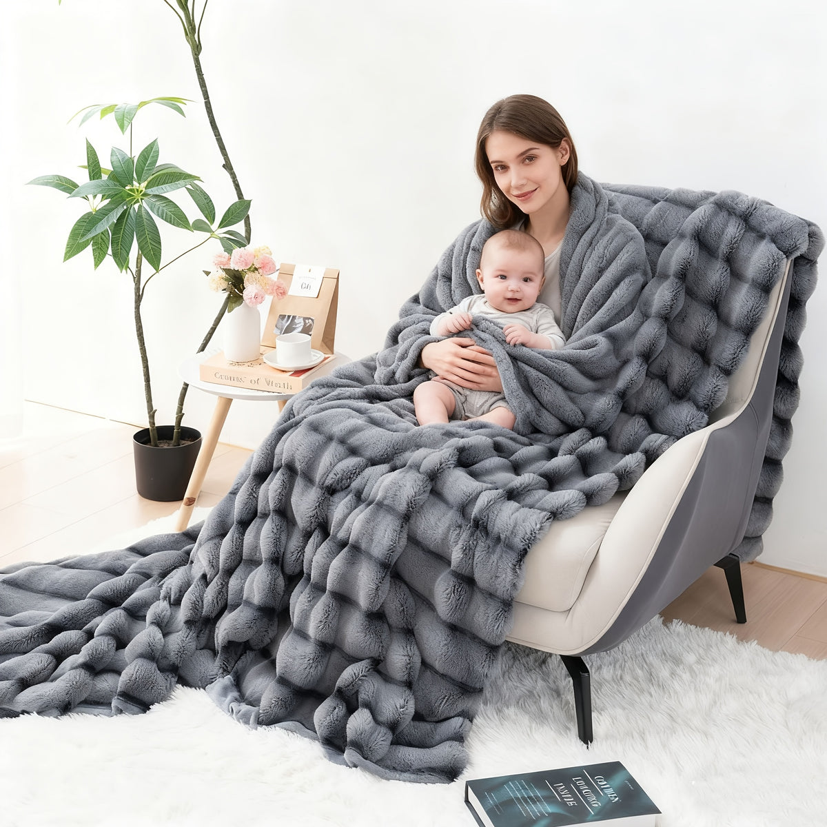 Woman holding a child while covered with a gray ribbed faux fur blanket.