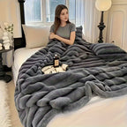 Woman seated on a couch with a dark gray ribbed faux fur blanket.
