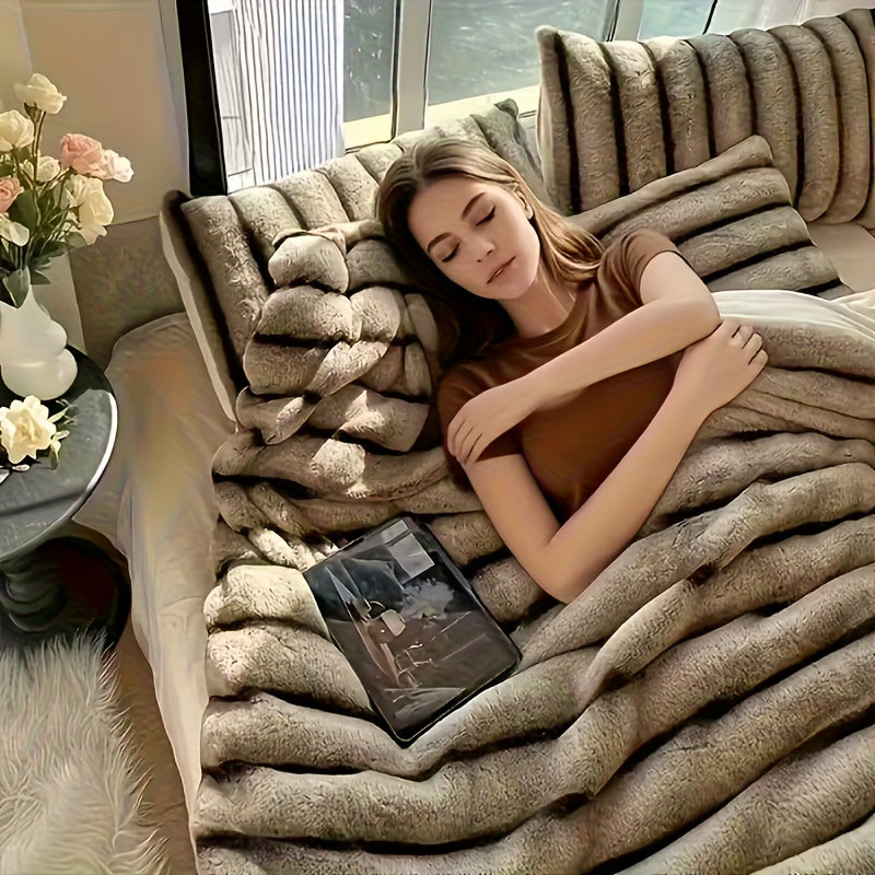 Woman resting on a couch under a brown tipped ribbed blanket.