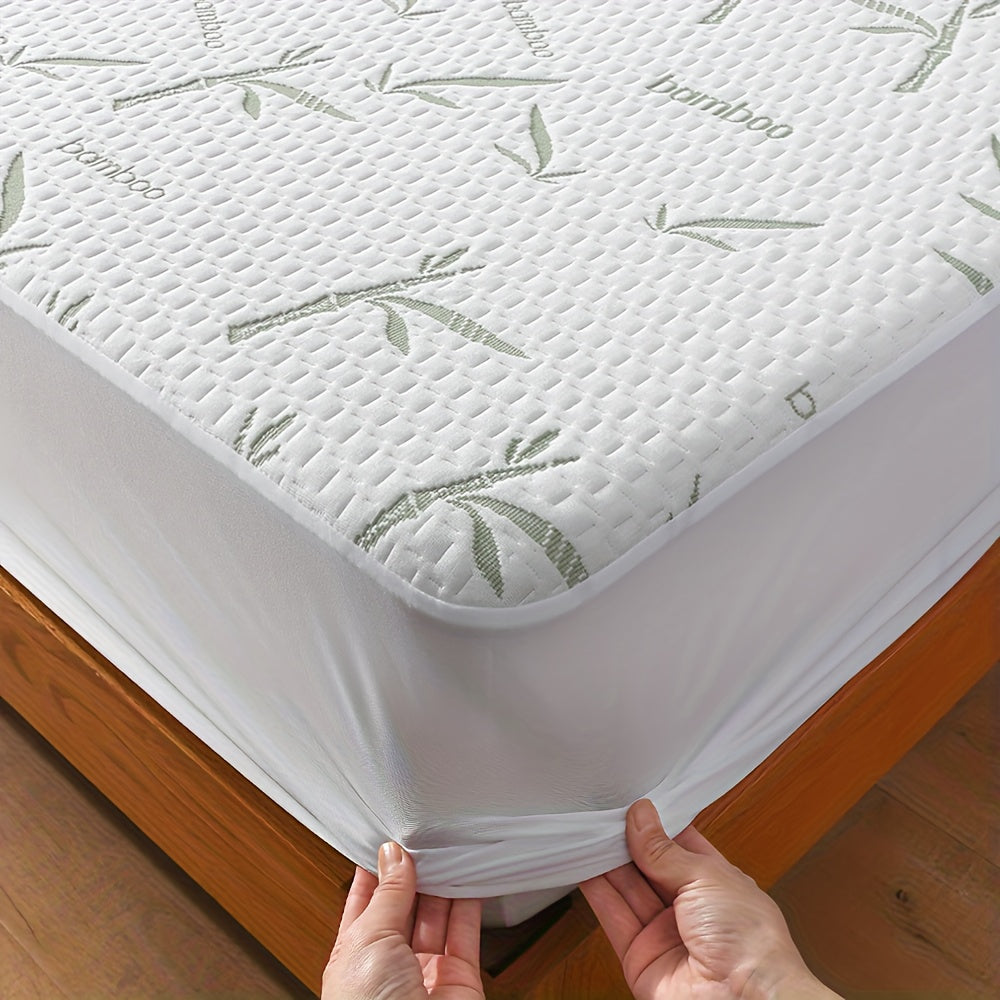 White fitted mattress protector with green leaf pattern and elasticized side skirt