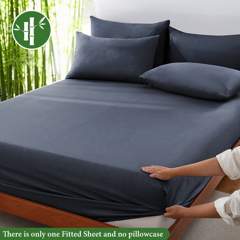 Dark gray fitted sheet displayed on a bed with a bamboo graphic