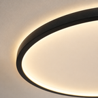 Circular flush mount ceiling light close-up showing the black rim and glowing diffuser.