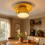 Yellow flush mount ceiling light glowing above a dining table in a warm kitchen and dining area.
