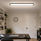 Flush mount ceiling light illuminating a neutral living room with a sofa and wall clock.