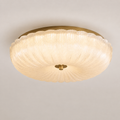 Flush mount ceiling light with a pleated translucent shade, warm glow, and small brass center detail.