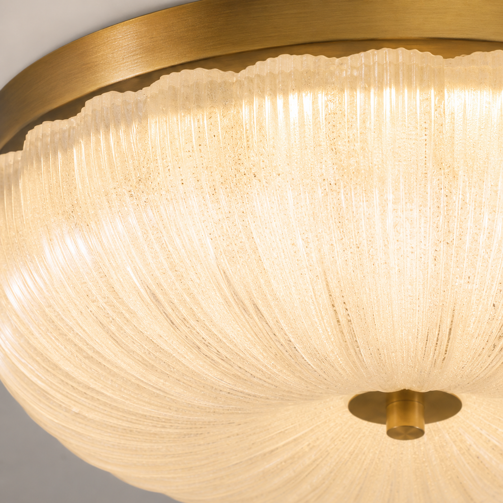 Flush mount ceiling light close-up showing the layered pleated shade, warm illumination, and brass center fitting.