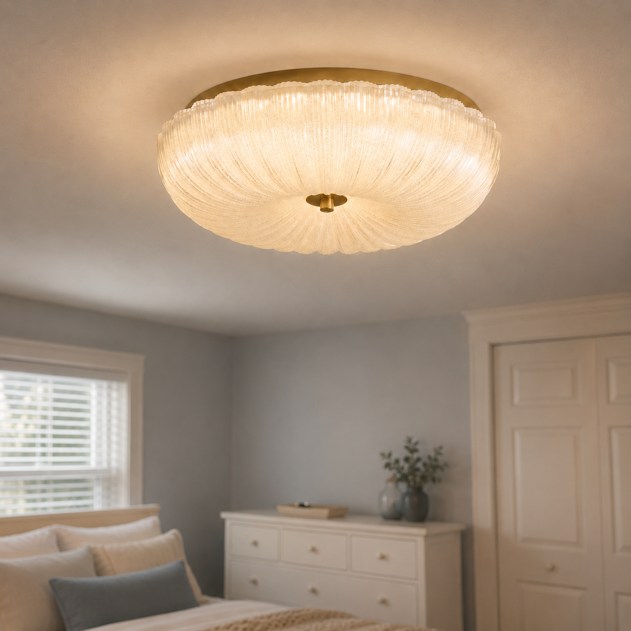 Flush mount ceiling light glowing above a bright bedroom with a dresser, window, chair, and plant.