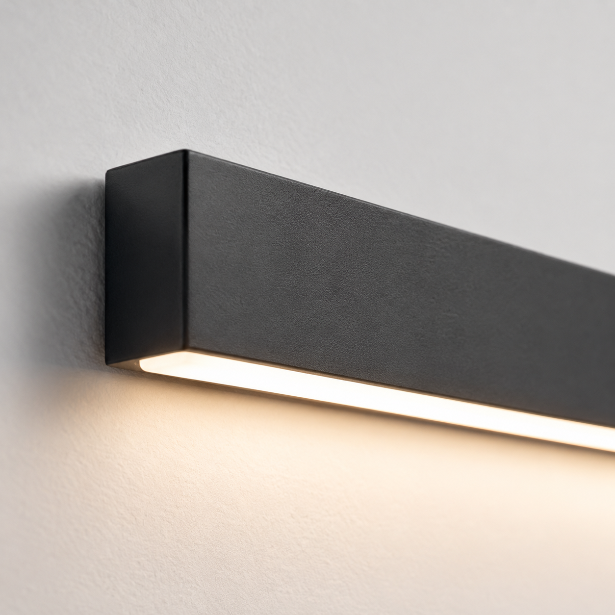 Close-up wall light view showing the black rectangular body and downward glow.