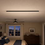 Slim black wall light mounted near the ceiling in a softly lit living room.