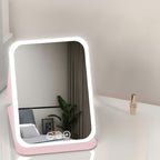 Pink foldable makeup mirror on a tabletop
