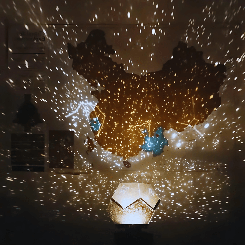 Galaxy projector casting bright star patterns around two people in a dark room.
