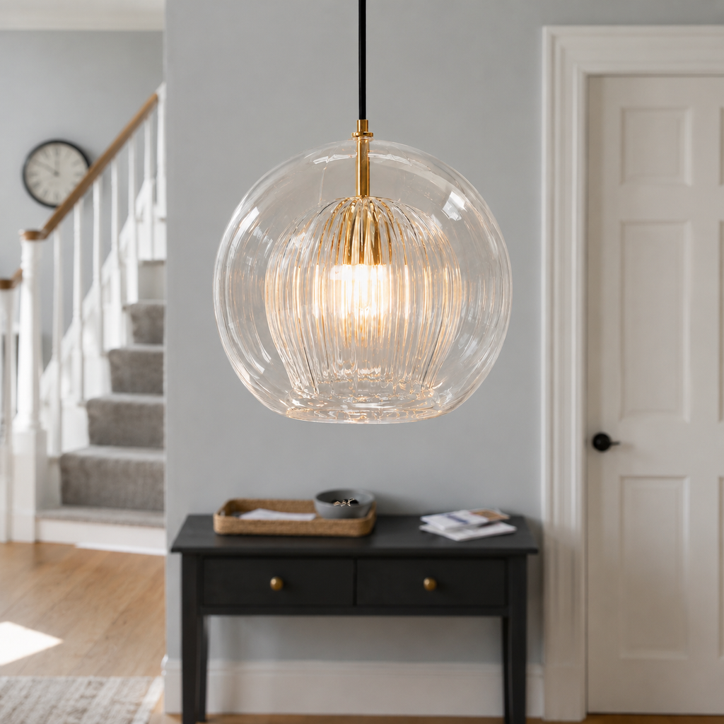 Ribbed glass pendant light suspended over a black console table in a bright entryway.