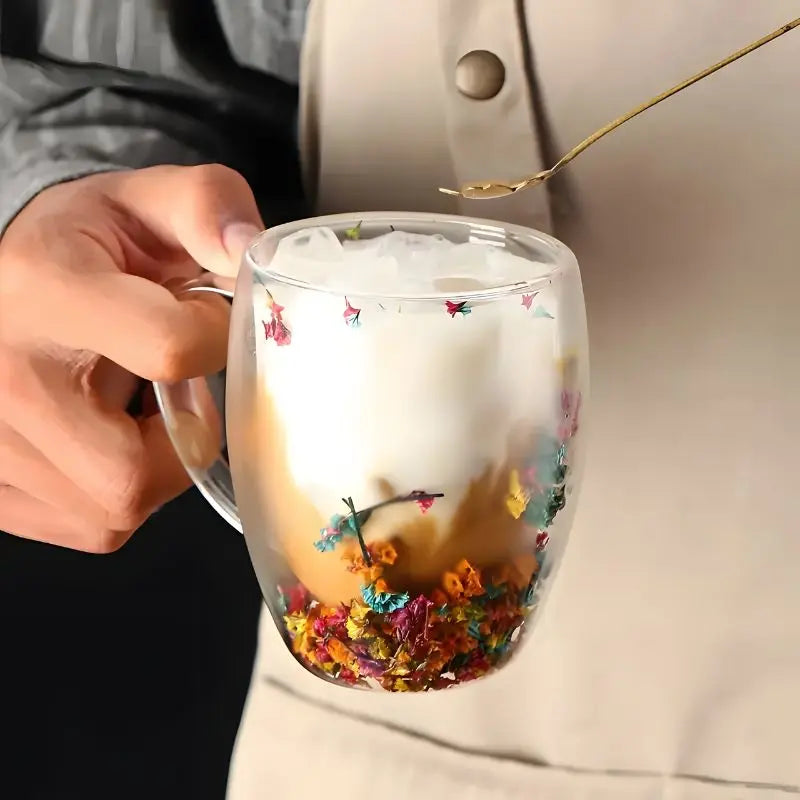 Floral double wall glass mug held while a drink is stirred