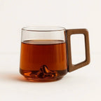 Smoky glass mug filled with tea, showing a mountain detail at its base