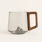 Empty smoky glass mug with sculpted mountain base and wooden handle