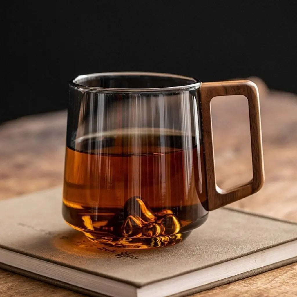 Smoky glass mug filled with tea, showing a mountain detail at its base