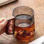 Smoky glass mug filled with tea, showing a mountain detail at its base