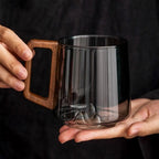 Empty smoky glass mug with sculpted mountain base and wooden handle